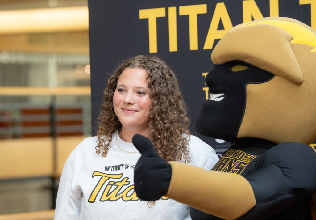 Girl and UW-Oshkosh mascot Clash smiling and giving a thumbs up.