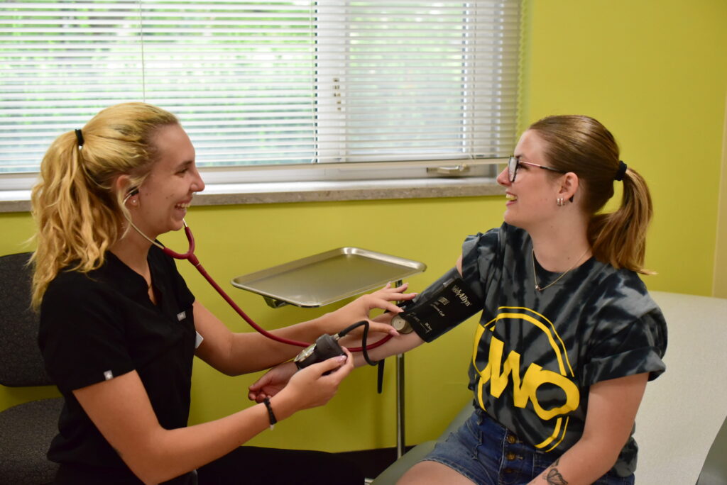 Nurse smiling while taking a students blood pressure in the Student Health Center.